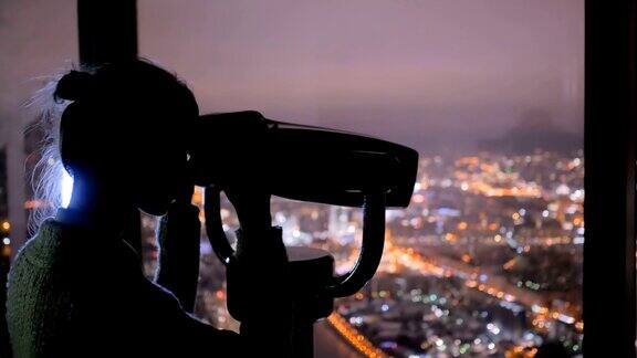 年轻女子通过旅游望远镜探索城市夜景