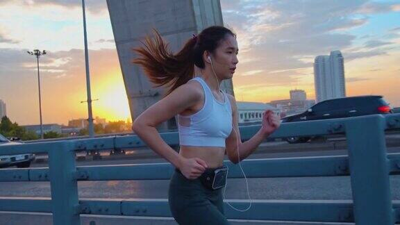 日落年轻女子慢跑过桥的慢镜头