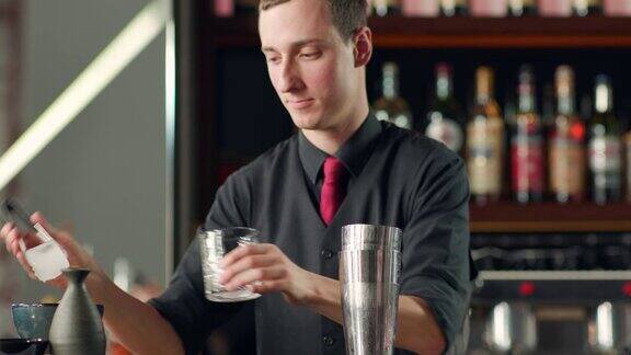调酒师用镊子将冰块放入玻璃杯
