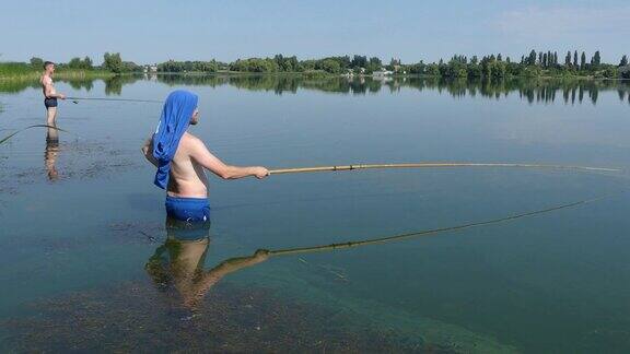 一个人拿着钓竿在湖边钓鱼渔民们在阳光下站在湖边