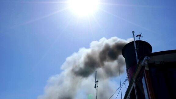 蓝色的天空中黑烟从烟囱里冒出来