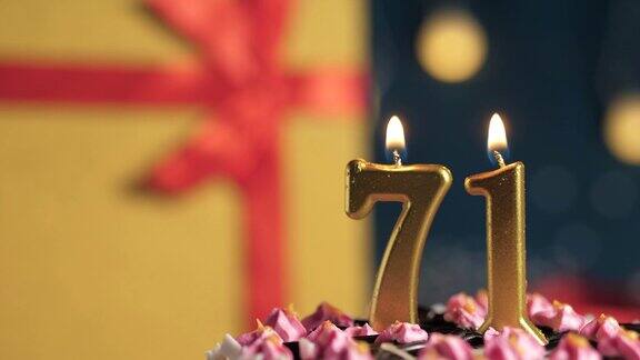 71号生日蛋糕用金色蜡烛点燃蓝色背景的礼物用黄色礼盒系上红丝带特写和慢动作