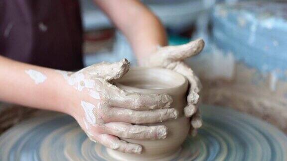 制作陶罐陶工陶土作坊陶土在装置上大师双手在陶土轮上工作塑造一个陶土壶