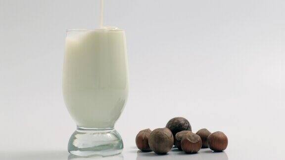 将鲜奶倒入白色背景的透明玻璃杯中健康食品和乳制品概念慢镜头飞溅与新鲜的白色营养饮料滴特写特写
