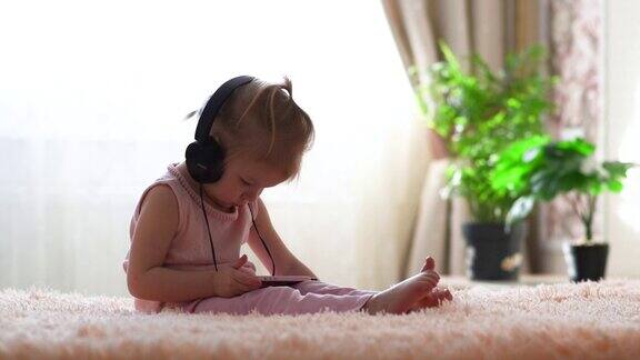 一个戴着耳机的小女孩正坐着看卡通片