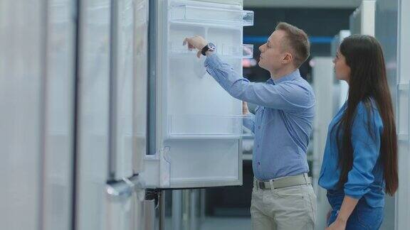 一男一女打开冰箱门在商店购买前检查设计和质量