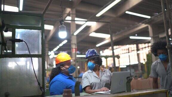 工厂工人在开非正式会议在笔记本电脑上分析信息