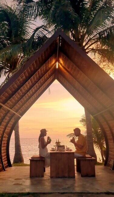日落时分一对男女在泰国麦岛的海滩上享受浪漫的晚餐