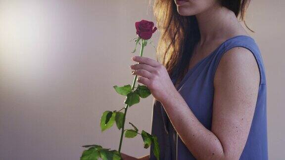 手持一朵红玫瑰的年轻女子