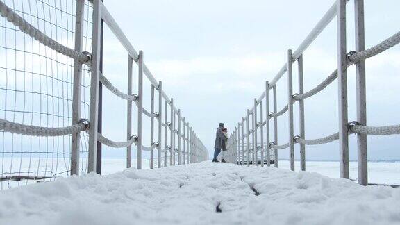 一个男人在白雪覆盖的码头上拥抱了一个女孩长时间拍摄