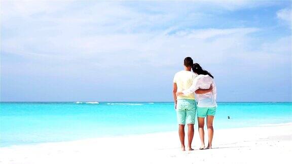 一对年轻夫妇在白色的海滩上度过暑假幸福的情侣享受他们的蜜月慢动作视频