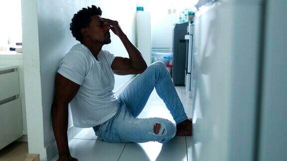 一个非洲人坐在厨房地板上受苦