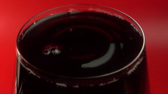 红色背景下的酒杯里的红酒玻璃杯里的酒滴