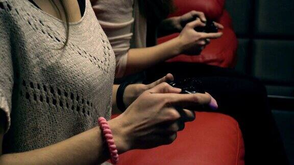 两个小女孩在红色沙发上用游戏手柄玩电子游戏