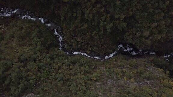 4K鸟瞰图瀑布与树木流动在挪威的森林自顶向下转折