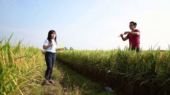 一个亚洲中国年轻女孩有一个有趣的周末在稻田与吹泡沫在早上与她的父亲