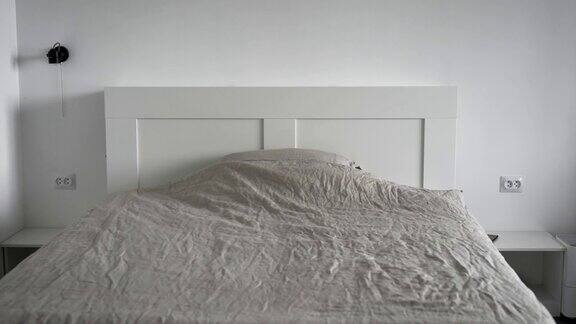 现代卧室的内部一个明亮的房间白色的墙壁一张宽大的床一条毯子和一个枕头