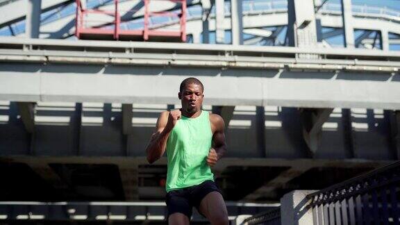 年轻的非洲运动员在城市桥上练习倒跑练习时积极地呼吸