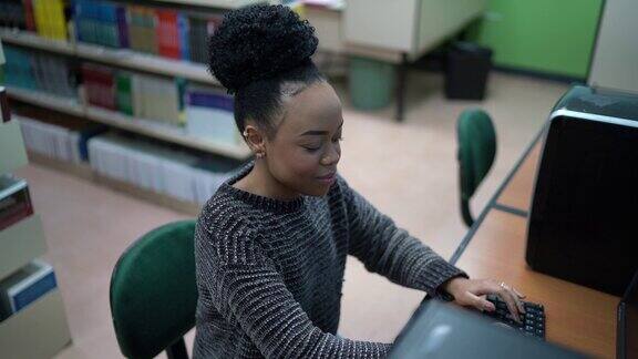 一个快乐的年轻女子在图书馆使用电脑的肖像