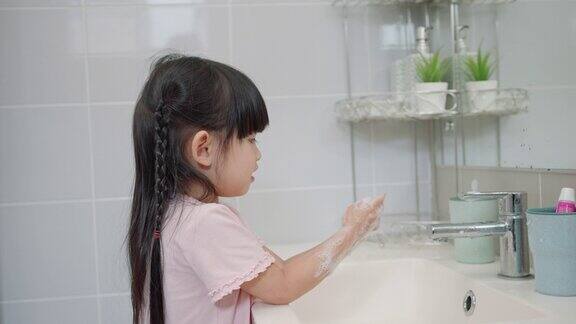 亚洲小女孩在厕所用肥皂和水洗手以保持卫生和预防病毒感染