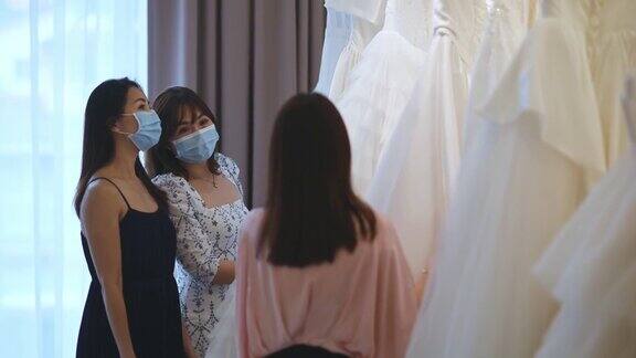 亚洲华人新娘服装店老板向她的顾客解释新娘的婚纱和面膜