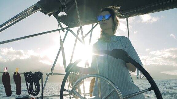 一位戴着墨镜的女士在掌舵的时候驾驭着一艘船