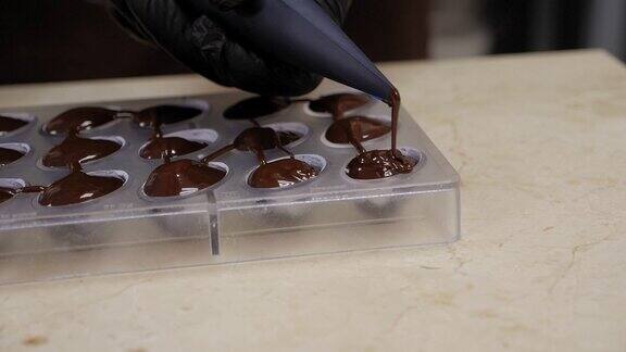 一个糕点师用融化的巧克力填充糖果模具的特写镜头