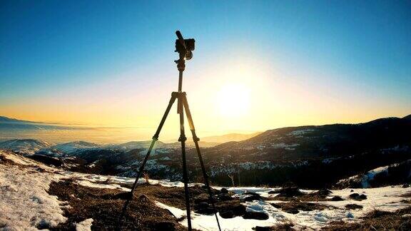 三脚架上的摄像机孤立在日出的背景下相机在三脚架上的剪影与日出的山背景