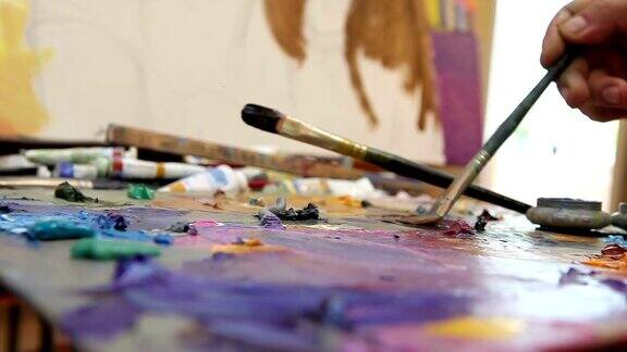 艺术家在工作室里画一幅油画画家在工作创造者制作一件艺术品刷子和颜料