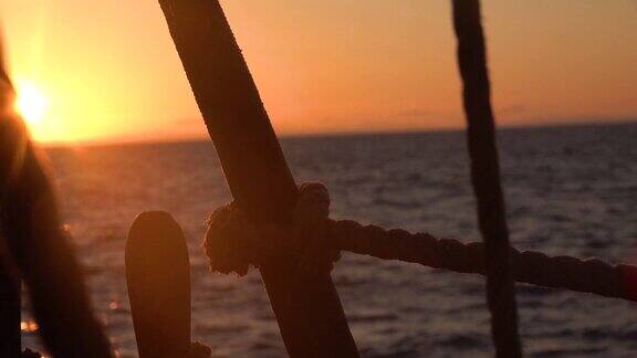 透过一艘旧帆船的护桅索具看日落海景慢动作视频