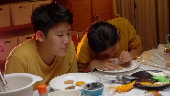 亚洲孩子晚上在家里一起装饰饼干万圣节的生活理念