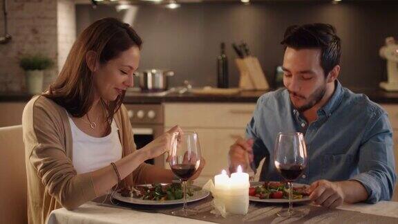 一对美丽的夫妇在厨房里吃烛光晚餐他们吃喝聊天两个都有好心情和微笑很多缓慢的运动