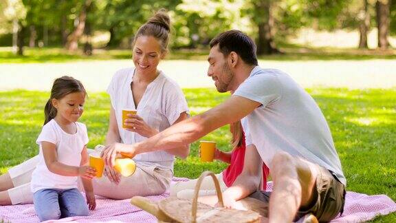 快乐的家庭在公园野餐喝果汁
