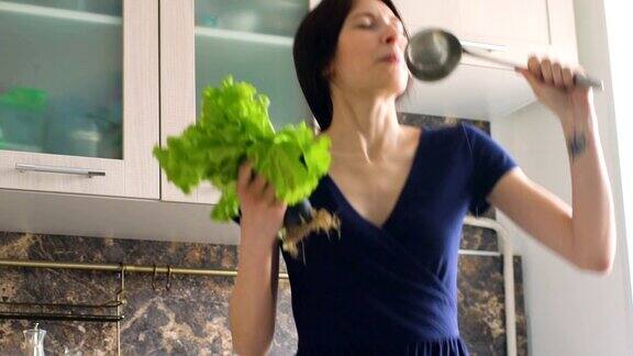 在厨房做饭时滑稽的女厨师用大勺和莴苣跳舞唱歌的慢动作