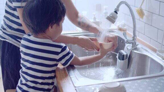 年轻的亚洲妇女和婴儿在厨房洗碗