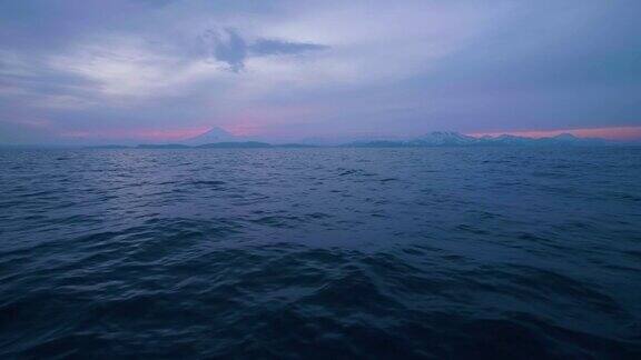 傍晚日落的天空与云在山上和蓝色的海浪在表面