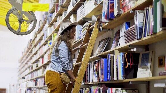 女孩在梯子上挑选书架上的书