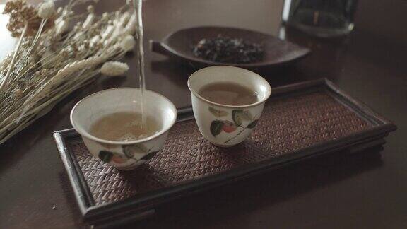 将滚烫的中国茶倒入漂亮的陶瓷茶杯中