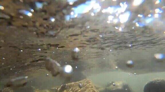 浅河底部的石头气泡和快速强劲的水流水面的特写