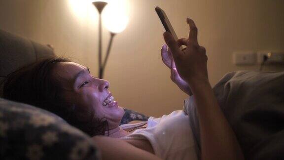 亚洲女性晚上睡觉前在床上使用智能手机