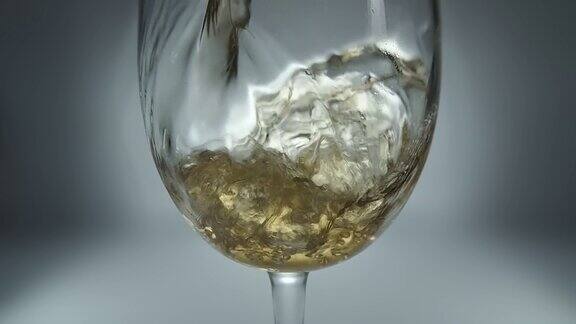 创意宏慢动作原始视频白葡萄酒倒进玻璃杯玻璃与倒白葡萄酒的特写与溅和泡沫