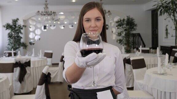 一个年轻的女侍酒师拿着一杯红酒的特写镜头