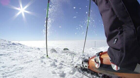 慢镜头特写:滑雪者从山顶的滑雪板上取出新雪