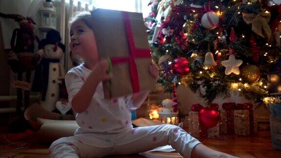 圣诞节早晨兴奋的孩子在打开礼物之前摇晃着它们