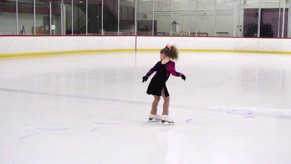 小女孩在室内溜冰场练习花样滑冰