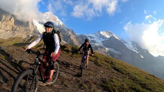 向后看骑自行车的女性沿着山脊骑车