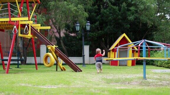 蹒跚学步的婴儿在户外操场上玩耍婴儿在草地上奔跑