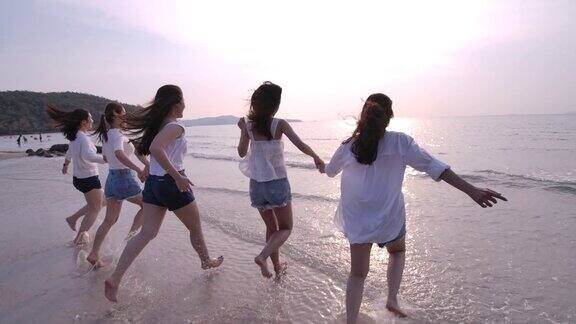 在日落下一群女孩在沙滩上奔跑