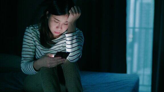 孤独的女人坐在床上用手机