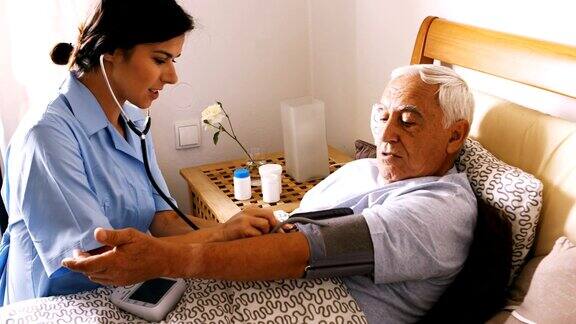 护士在卧室为老人检查血压